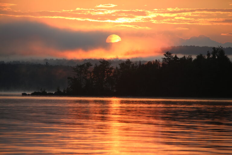 Golden sunrise with drifting mist over Lake Umbagog