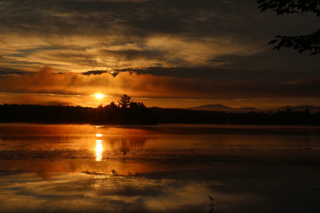 Warm sunrise light reflecting on the still waters of Lake Umbagog National Wildlife Refuge
