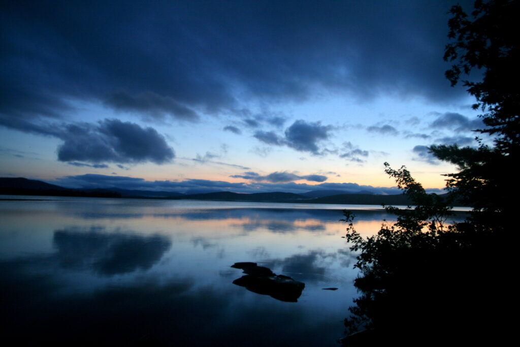 Blue and purple twilight reflecting on the still waters of Lake Umbagog at the Maine–New Hampshire border.