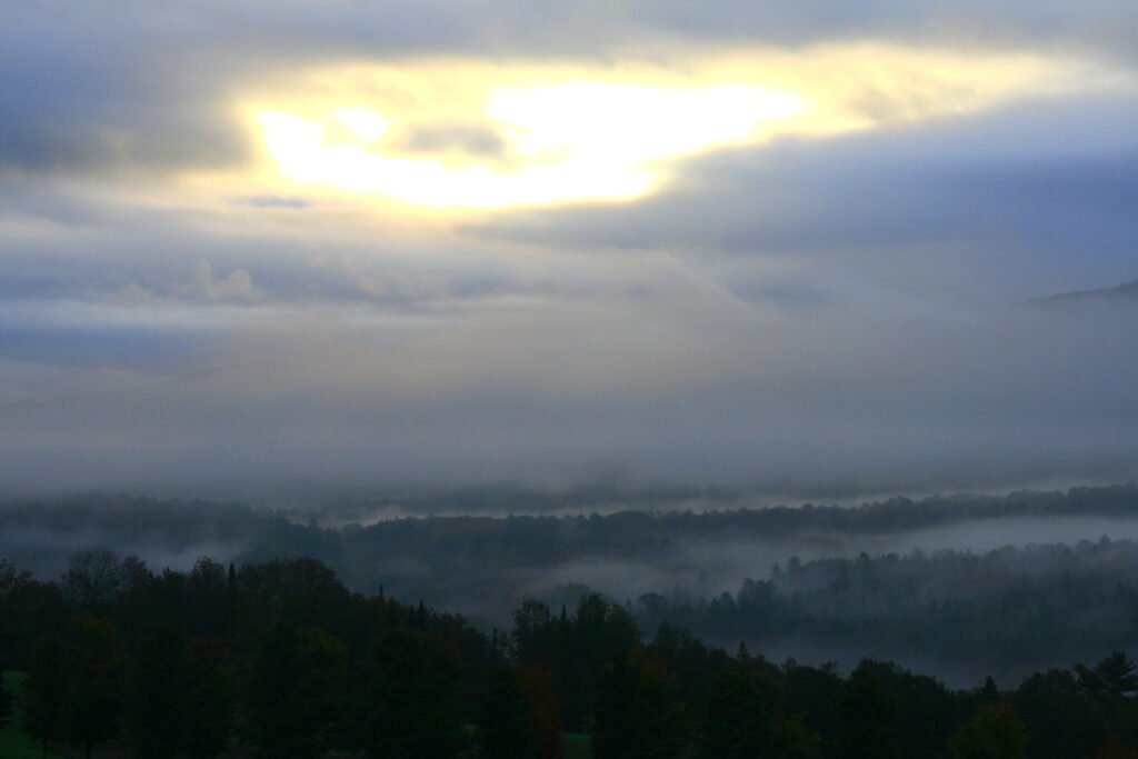 Rain and mist at sunrise in Lyndonville, Vermont with soft golden light, peaceful New England nature photography.