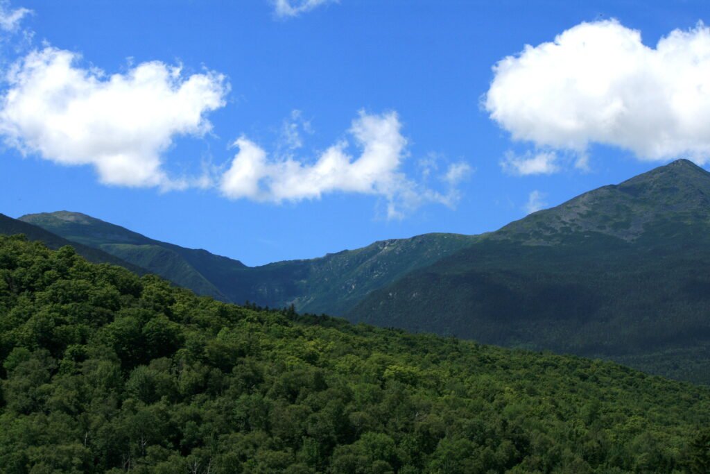 New Hampshire mountain ridges beneath a bright blue sky and drifting summer clouds near Littleton