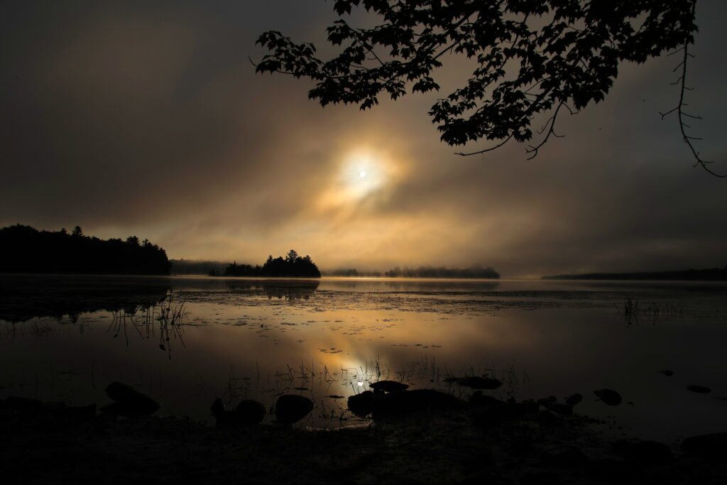 Misty sunrise over Lake Umbagog National Wildlife Refuge in New Hampshire with fog across calm water