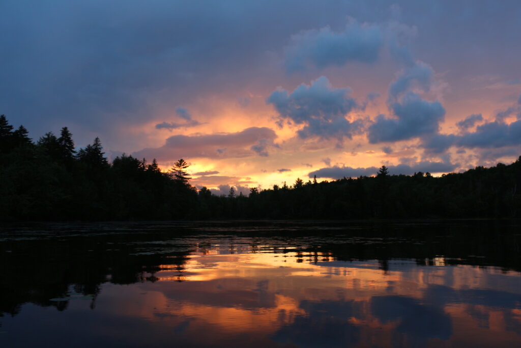 Calm water reflecting soft post-sunset colors and distant shores after dusk on Lake Umbagog in the Lake Umbagog National Wildlife Refuge, New Hampshire and Maine